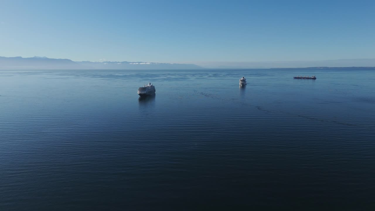 Aerial view of cruise ships sailing on a sunny day near Puerto Montt, Chile, with mountains in the background