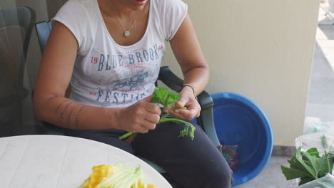 mujer prepara flores de calabacín para la comida tradicional de kalamata al aire libre