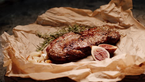 Saftiges-Gourmet-Steak-Auf-Papier-Präsentiert-Mit-Rosmarin,-Feigen-Und-Knoblauchzehen