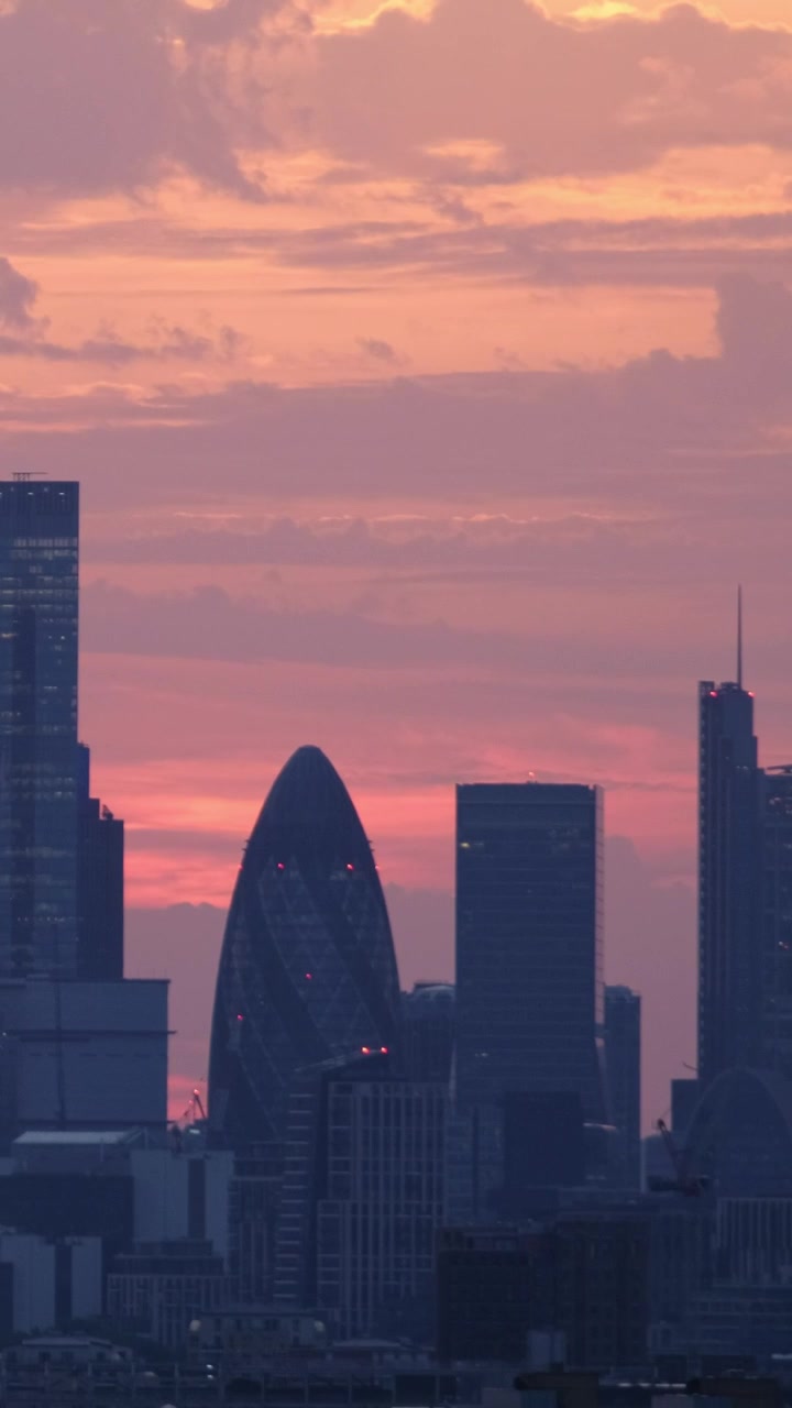 Vista vertical com teleobjetiva do horizonte de Londres ao pôr do sol, apresentando o Gherkin e o 22 Bishopsgate sob um céu de fim de tarde rosa e laranja