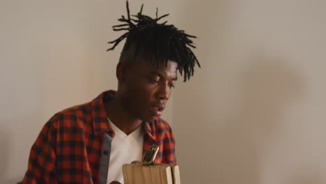 Focused-african-american-craftsman-with-dreadlocks-preparing-belt-in-leather-workshop