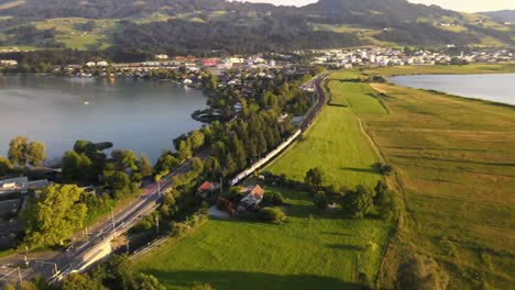 aerial drone shot showing sbb train driving towards rapperswil on a summer evening