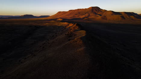 Drone-tilt-up-over-mountain-ridge-sunset-view-of-semi-arid-Karoo-landscape