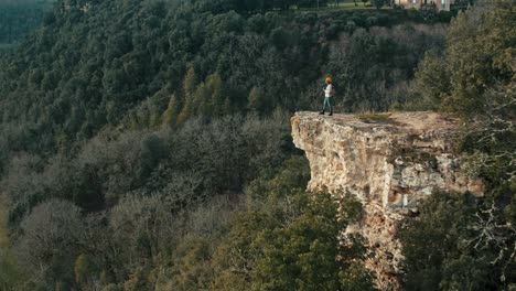 una mujer sola en un acantilado toma fotos de la naturaleza, una amplia vista aérea con una toma de seguimiento frontal