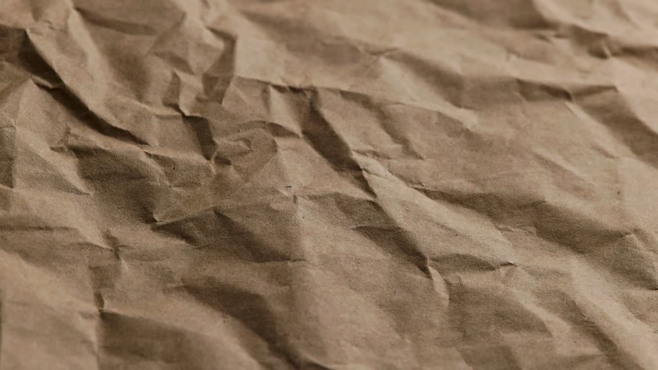 looped spinning close-up full-frame background of crumpled brown craft paper