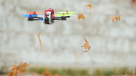 the drone flies quickly and low above the ground lifting leaves from the ground in the wind