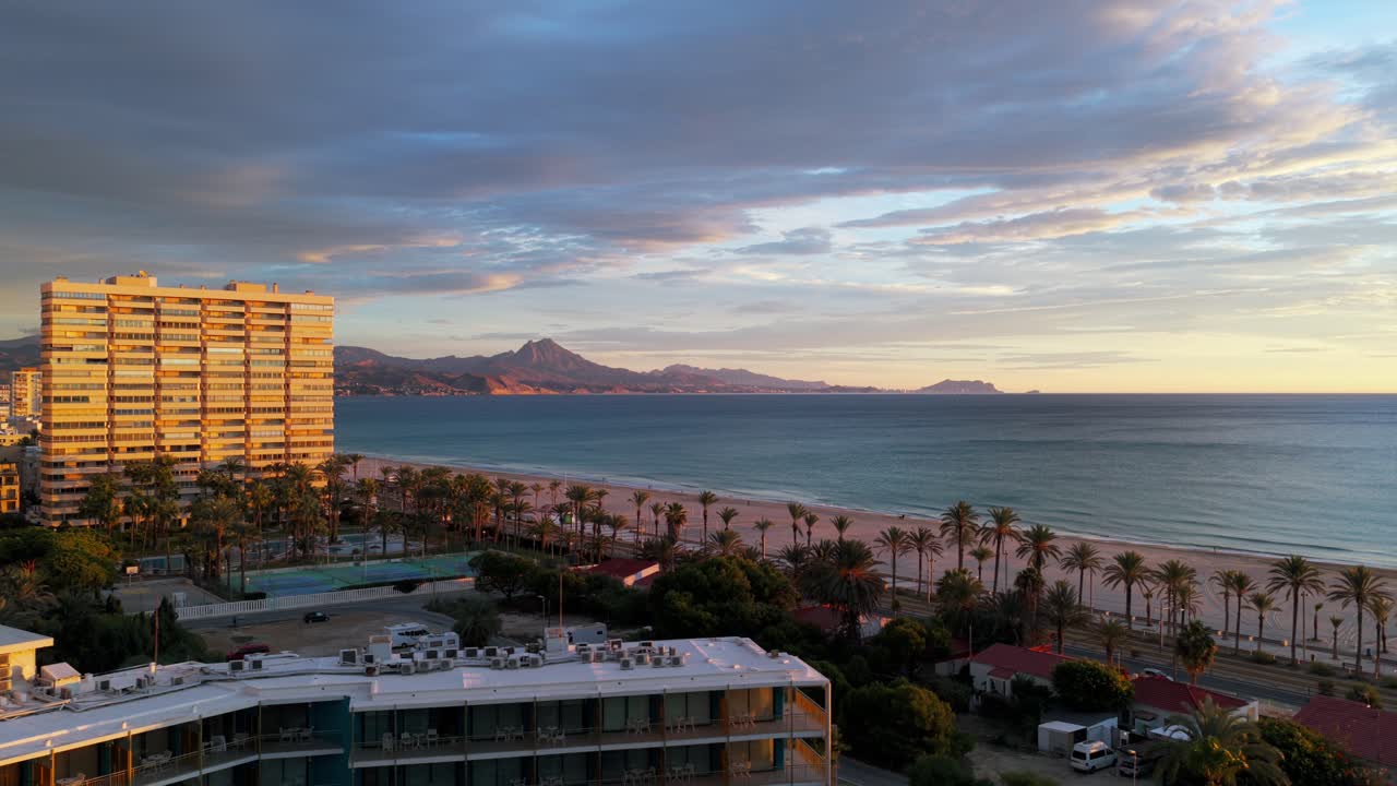 Condomini e hotel sul lungomare illuminati dalla splendida luce dell'ora d'oro all'alba ad Alicante, Spagna. Vista aerea con drone.