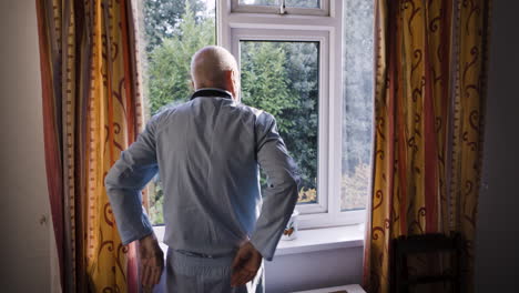 Elderly man looking out of window