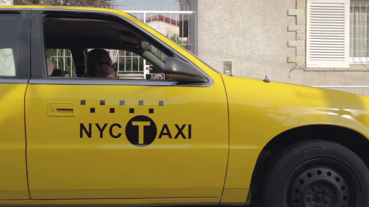Táxi amarelo de Nova York dirigindo e parando em uma rua residencial