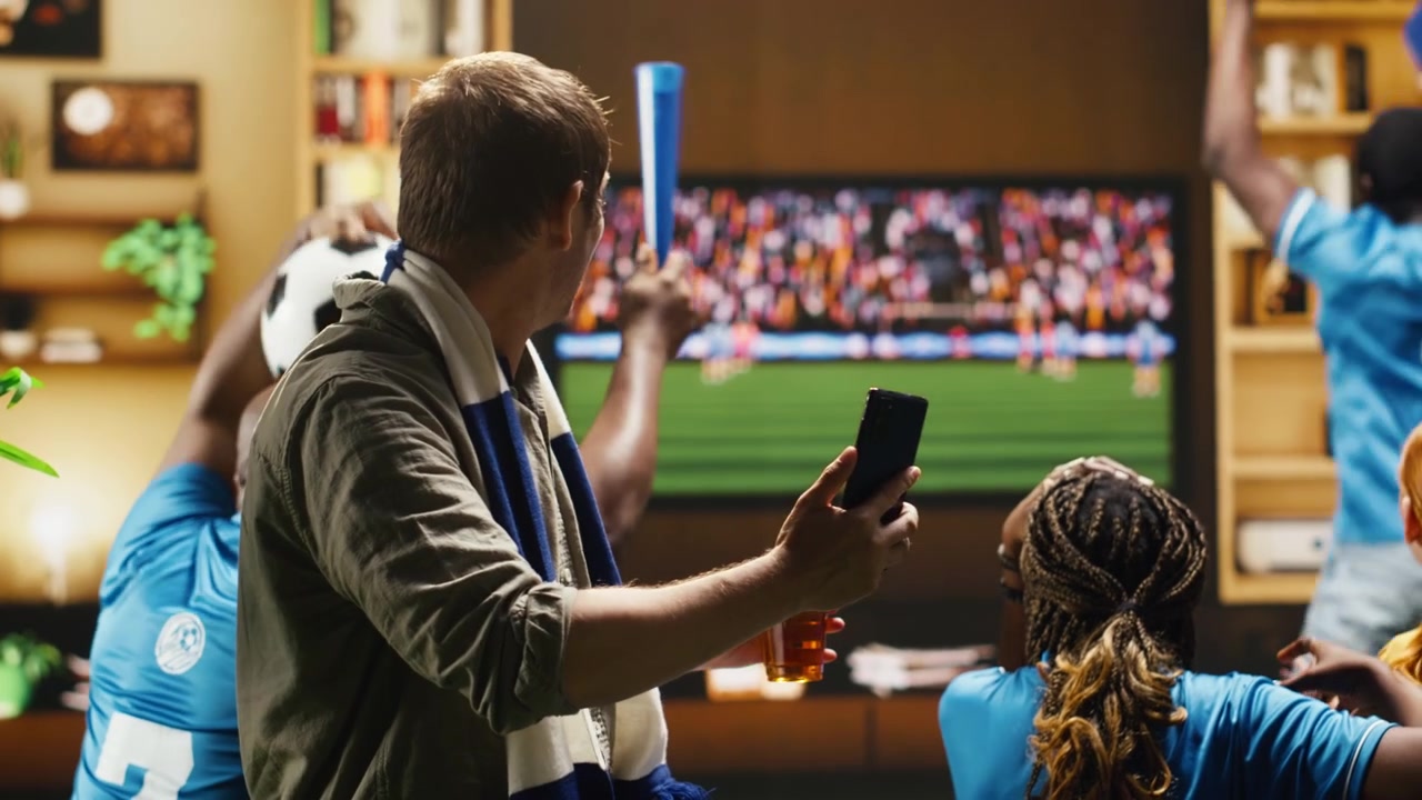 Primo piano di un tifoso di calcio a casa sul divano con lo smartphone in mano.