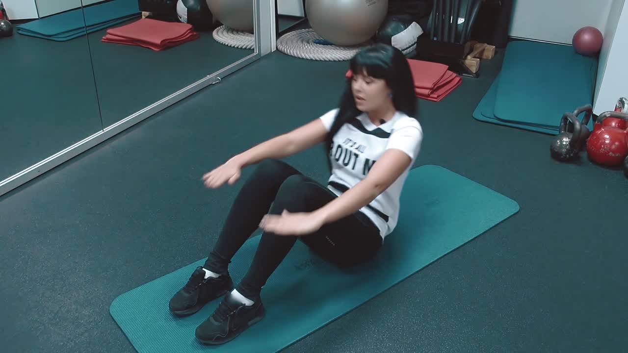 joven hermosa en el gimnasio bombea los músculos de la prensa acostado en el karemate sonriendo cámara lenta