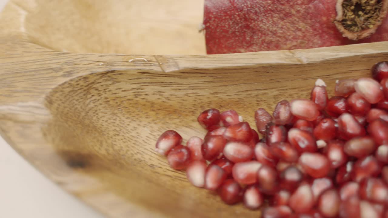 Panorering af granatæblekerner i træskål, presser saft og bruger friske ingredienser samt friske hele granatæbler