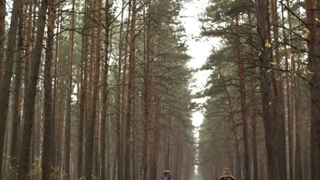 Rückansicht-Eines-Paares-In-Winterkleidung,-Das-Bei-Regen-Fahrrad-Im-Wald-Fährt-1