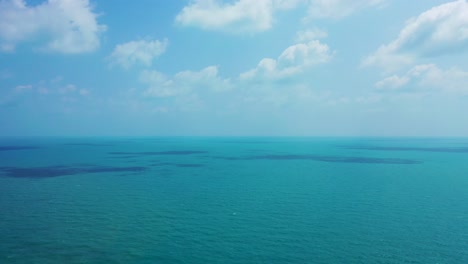 ocean background, bright blue sky with white clouds and tranquil water at open sea approaching horizon