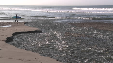 Surfer,-Der-Durch-Das-Wasser-Geht,-Das-Aus-Der-Mündung-Des-Ventura-Flusses-Am-Surfers-Point-In-Ventura-Kalifornien-Fließt