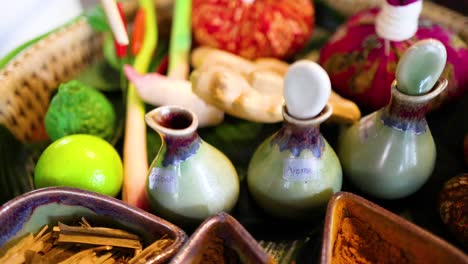 una mano selecciona ingredientes herbáceos de una bandeja vibrante para un masaje tailandés tradicional, mostrando elementos naturales y prácticas culturales