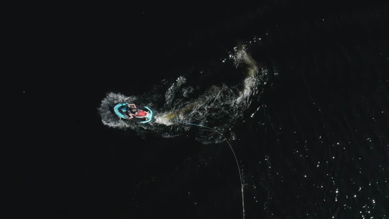 vista aérea superior de un joven en un veloz jetski en aguas profundas y oscuras en suecia