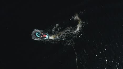 aerial top view of a young man on a speedy jetski in deep dark water in sweden