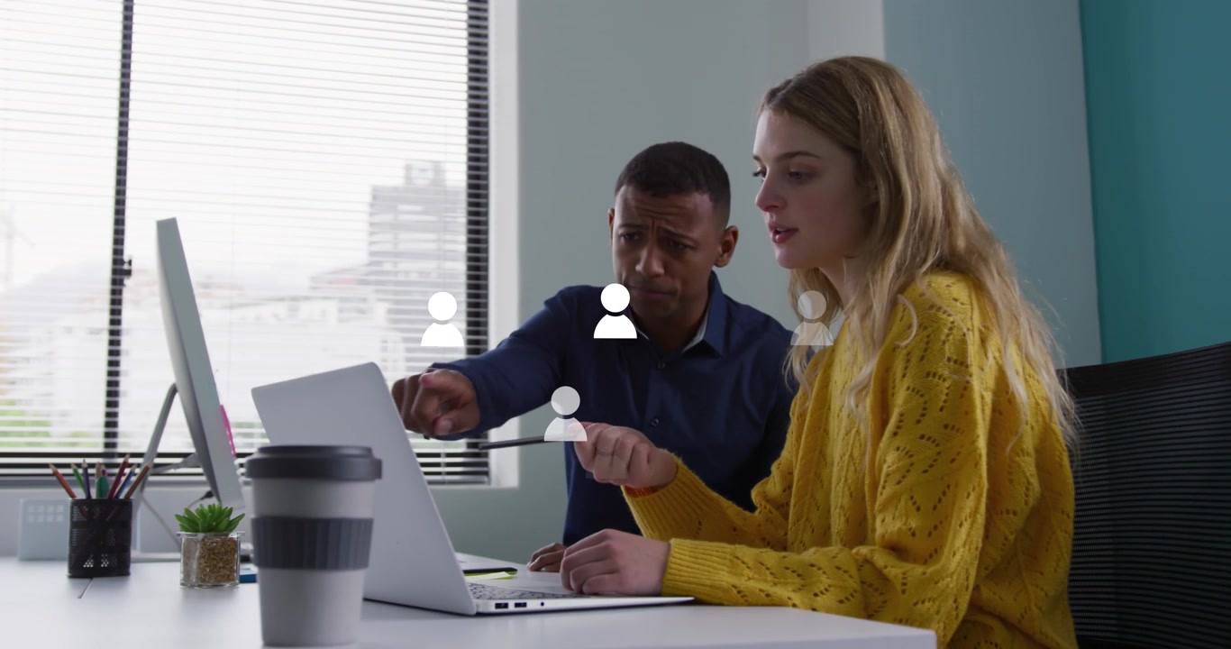 Animation of profile icons floating against diverse man and woman discussing over a laptop at office