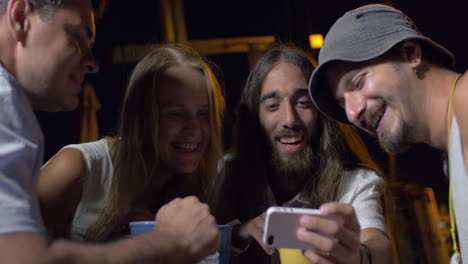 friends laughing at photos on mobile phone
