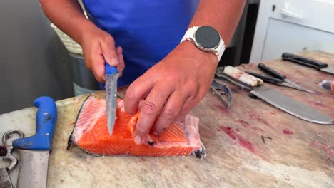 expert hands fillet fresh salmon on a wooden board