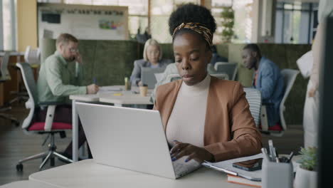 woman working on laptop in busy office