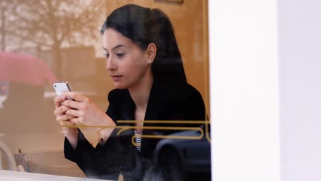 mujer usando teléfono móvil en una cafetería