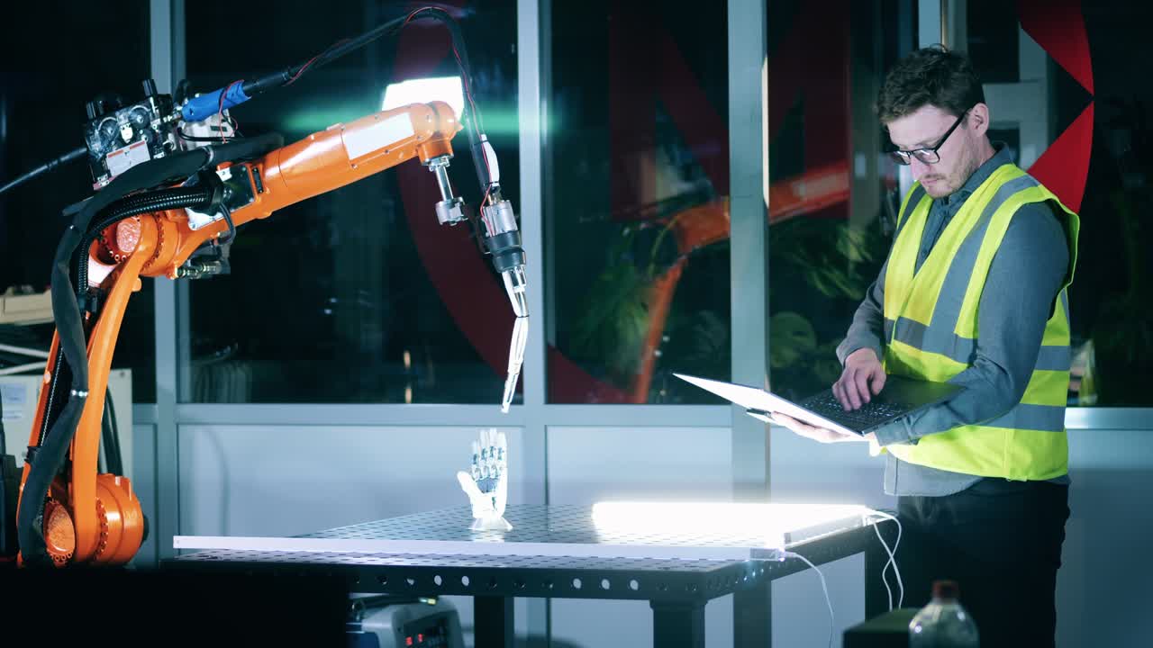 ingeniero masculino en ropa de seguridad está estudiando un mecanismo robótico