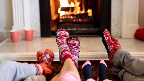 animation of feet of african american family in christmas socks resting in front of fireplace