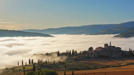 medieval village emerging from morning fog in tuscany