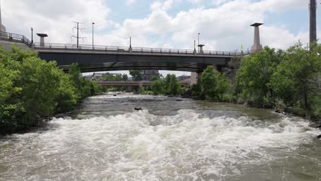 Drone-Sobre-El-Río-Retrocede-Bajo-La-Construcción-De-Acero-Del-Puente-En-La-Ciudad-De-Denver,-Colorado