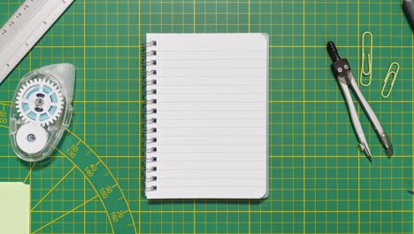 stop motion stationery frames a lined spiral notebook on green cutting mat, providing loopable copy space