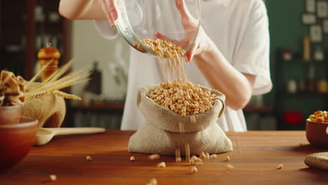 person pouring chickpeas into a burlap sack