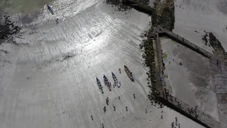 el avión no tripulado se eleva y se inclina hacia abajo por encima de los barcos de currach en la arena brillante y brillante