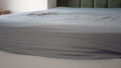 sábanas grises en un marco de cama blanco