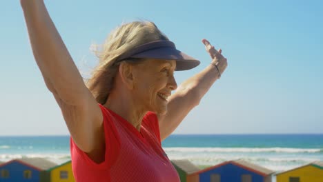 Side-view-of-active-senior-Caucasian-woman-standing-on-a-promenade-at-beach-4k