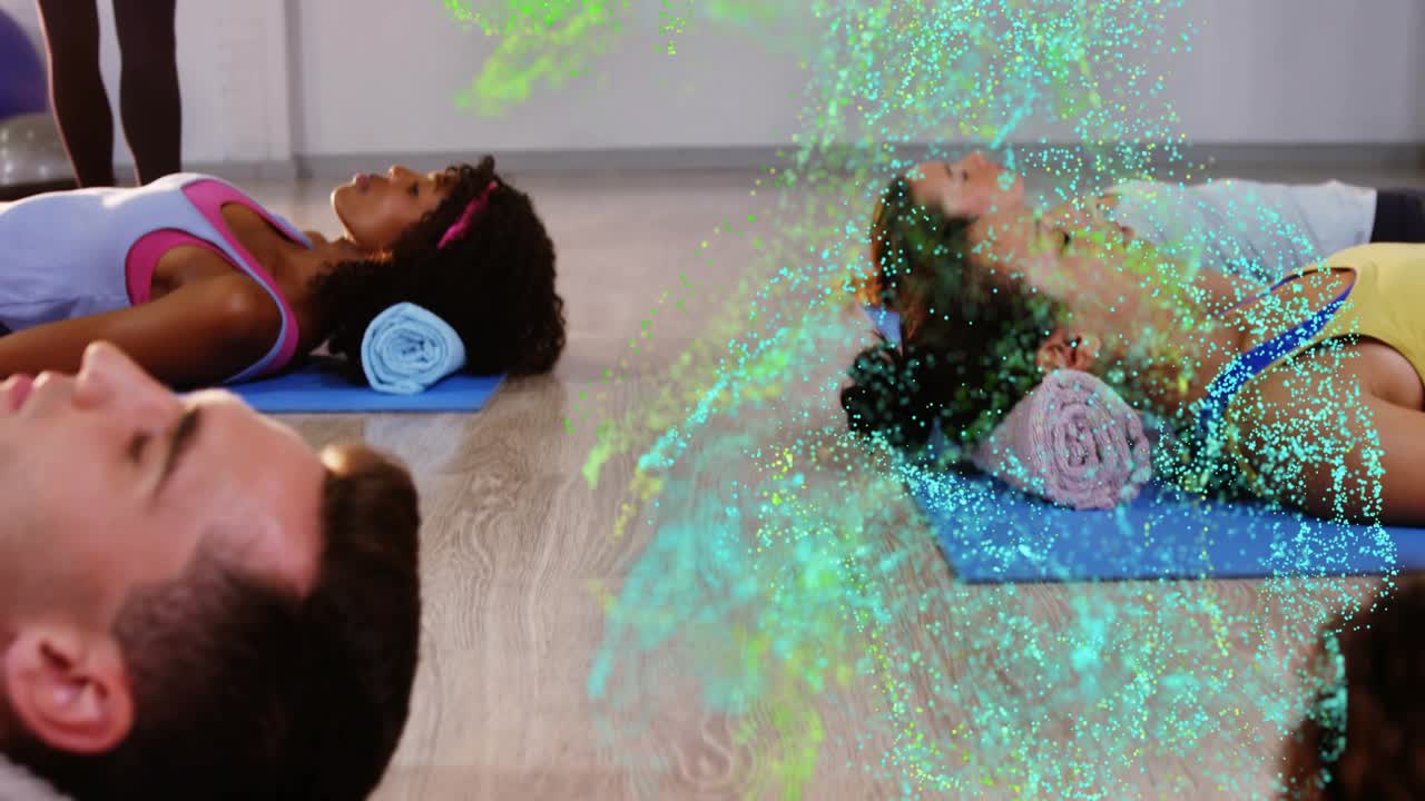 Two men lying on blue mats, green cyan particles emerging and sweeping torsos for wellness class