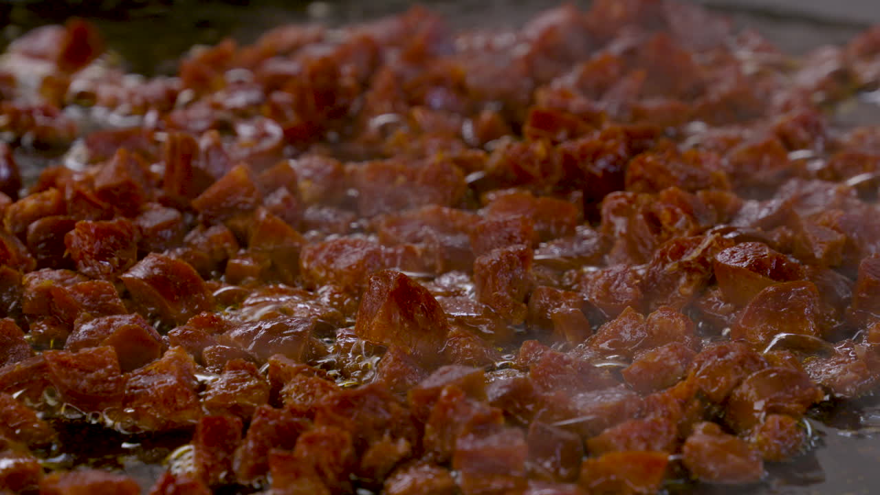 쌀 해산물과 많은 사프란을 곁들인 전형적인 스페인 요리인 빠에야 발렌시아나의 재료로 올리브 오일에 초리조를 튀기는 장면을 클로즈업합니다