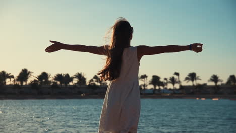 young female model with long hair enjoying summer at beautiful sand coastline.