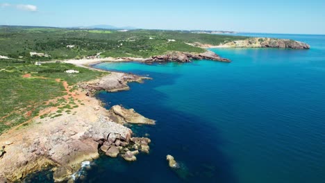 rocky coastline along the calm blue sea. - aerial shot