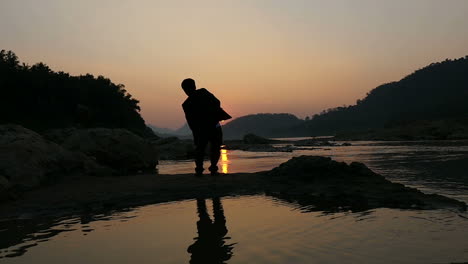 Silhouette of a Man Jumping at Sunset by the River