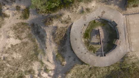 an aerial view of a defensive ww2 turret with preserved cannon on the coast of the baltic sea