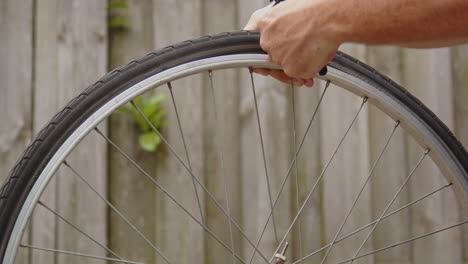 hand using tire lifters to remove bicycle tire and spinning wheel to fix flat tire