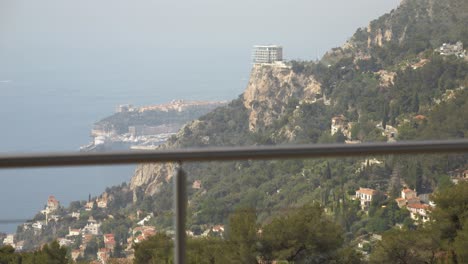 close-up-of-a-orchid-plant-with-a-breathtaking-view-in-the-background-of-a-bay-with-the-sea-and-rocky-mountains,-trees-and-houses-dotted-around