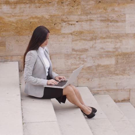 side view of woman using laptop on stairs