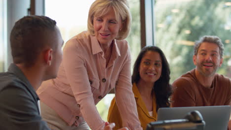 multi-cultural business team meeting around laptop in modern office