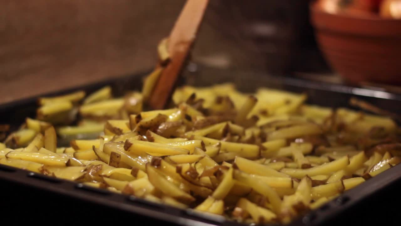 Appetizing oily french fries being arranged on a oven container