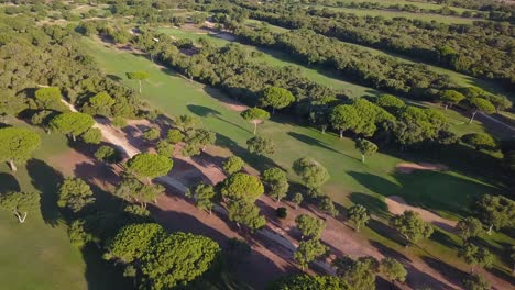 Toma-Aérea-Inclinada-Hacia-Abajo-De-Un-Campo-De-Golf-En-El-Sur-De-España-Con-El-Mar-En-El-Horizonte