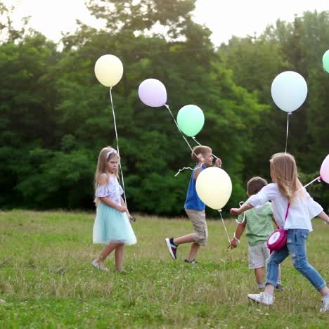 a little lovely kids outdoor with colorful baloons. happy childen are running on the green grass with colorful balloons in her hands. the concept of freedom, a child's dream, a happy family