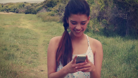 Pretty-brunette-texting-in-the-park